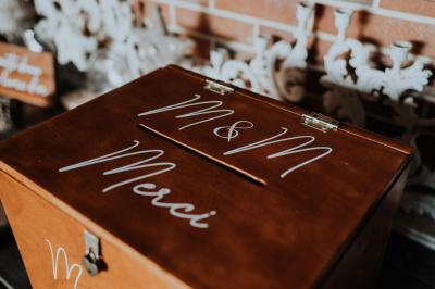 Costume de mariage bleu foncé avec chemise blanche et nœud papillon floral, suspendu sur un cintre gravé.