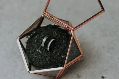 Costume de mariage bleu foncé avec chemise blanche et nœud papillon floral, suspendu sur un cintre gravé.