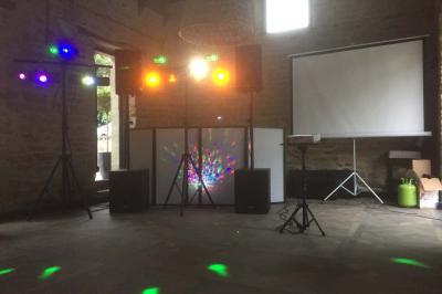 Installation de matériel de sonorisation et d'éclairage sous une tente, avec haut-parleurs et projecteurs colorés.