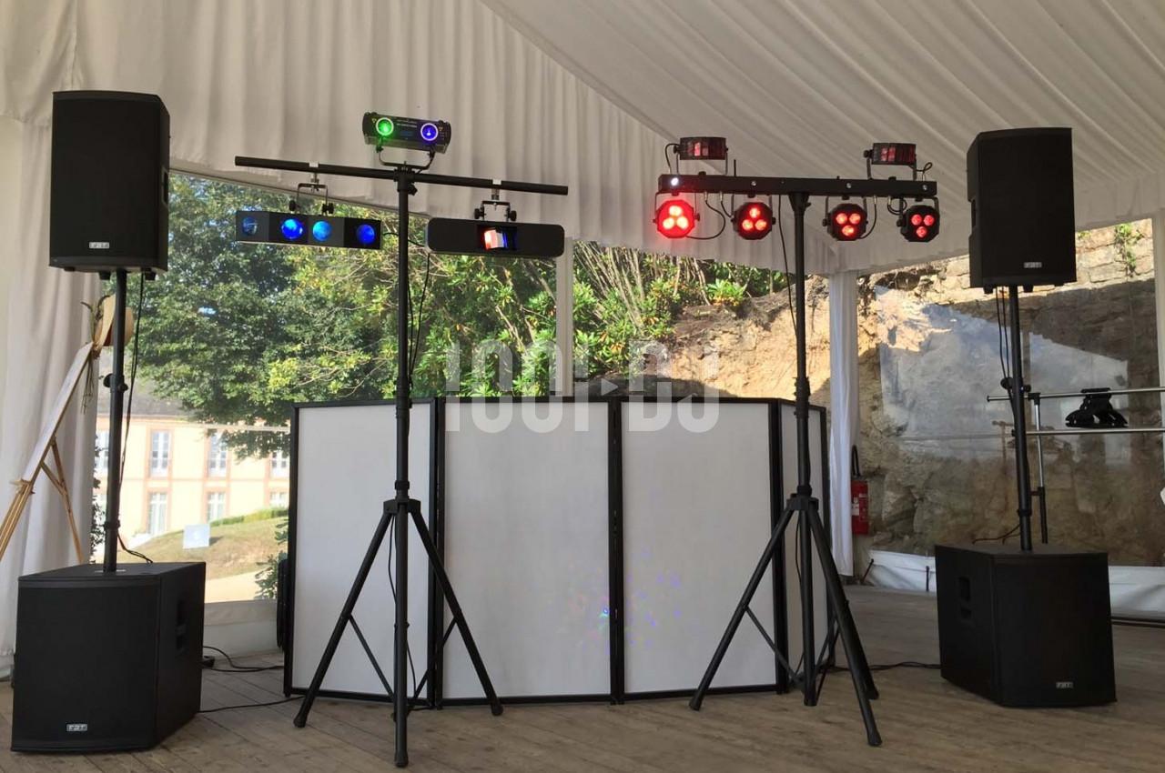 Installation de matériel de sonorisation et d'éclairage sous une tente, avec haut-parleurs et projecteurs colorés.