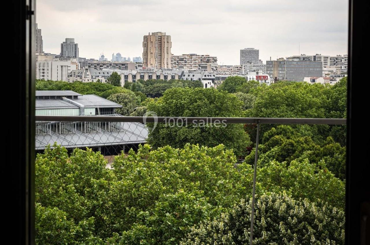 Vue sur une ville avec des immeubles modernes et des arbres verdoyants, encadrée par une balustrade au premier plan.