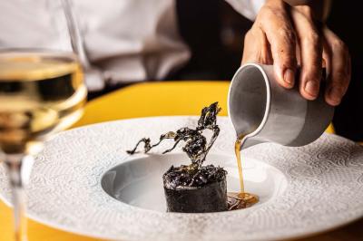 Miniature Location salle Paris 19 (Paris) - L'Envol de la Philharmonie #47 Un barman verse un liquide sombre dans un verre à cocktail rempli d'une boisson mousseuse.