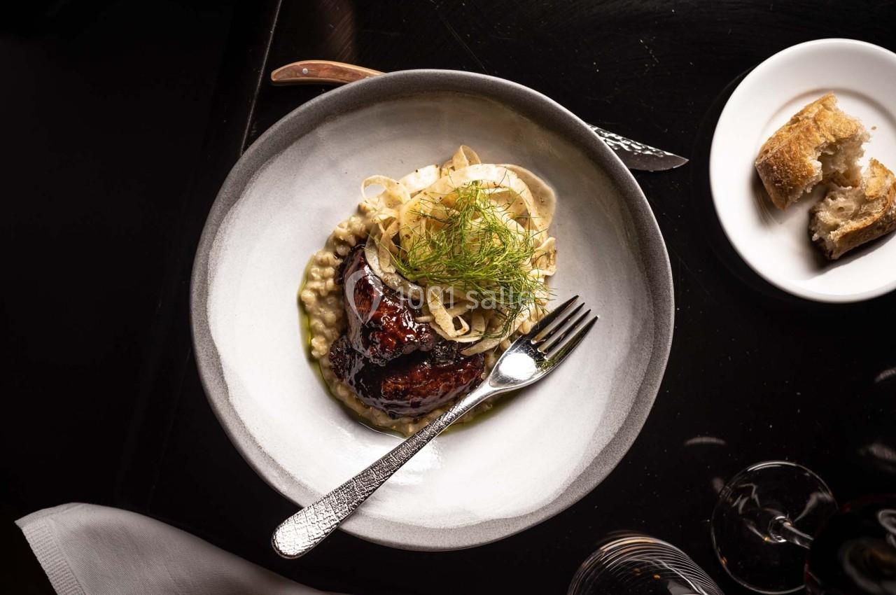 Assiette contenant un plat gastronomique avec viande laquée, purée crémeuse, fenouil et tranche de pain sur le côté.