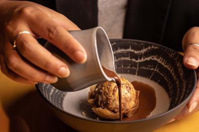 Miniature Location salle Paris 19 (Paris) - L'Envol de la Philharmonie #56 Un barman verse un liquide sombre dans un verre à cocktail rempli d'une boisson mousseuse.