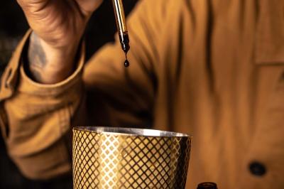 Miniature Location salle Paris 19 (Paris) - L'Envol de la Philharmonie #59 Un barman verse un liquide sombre dans un verre à cocktail rempli d'une boisson mousseuse.