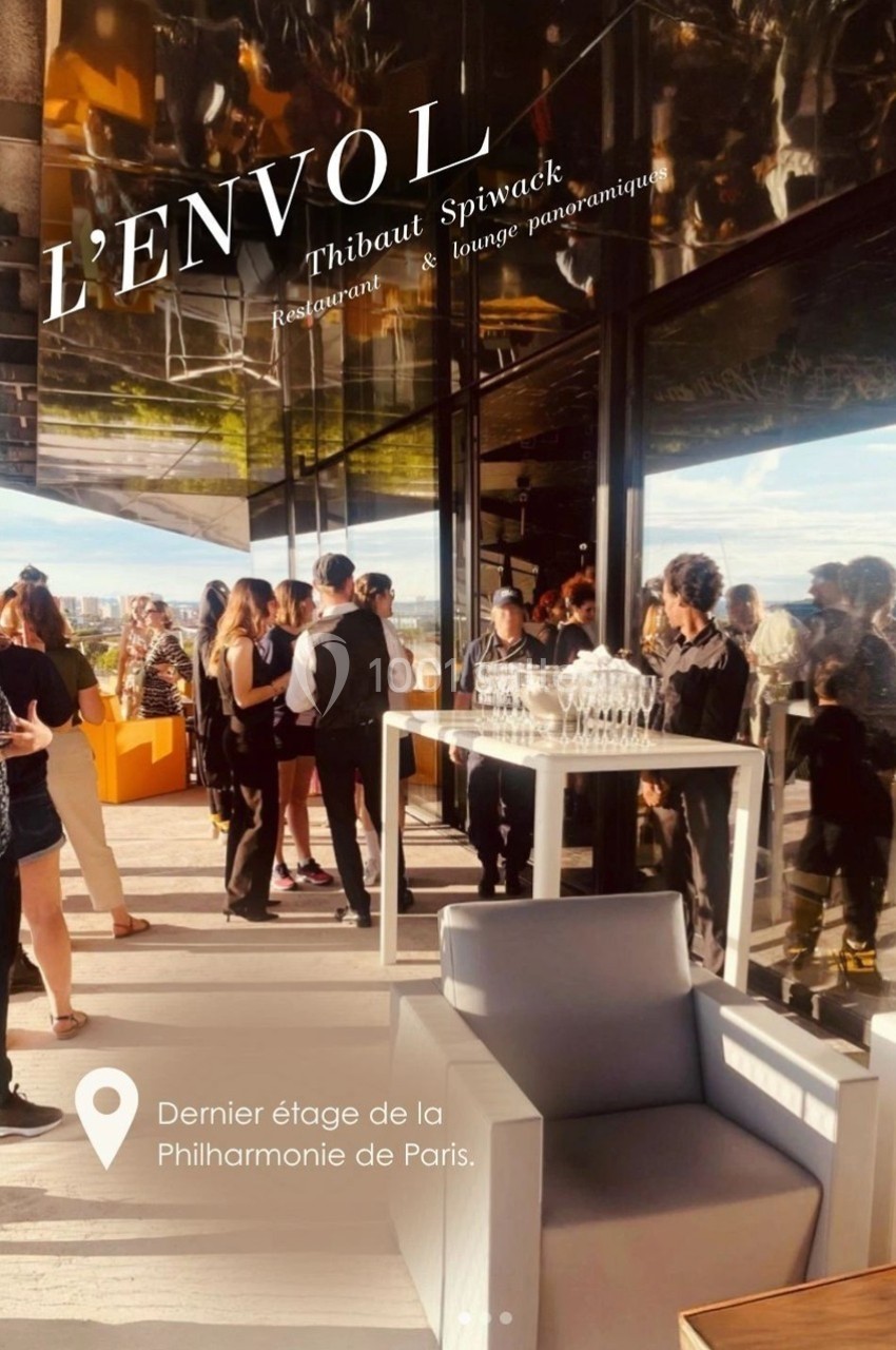 Terrasse animée d'un restaurant avec vue panoramique, serveurs et invités debout près d'une table dressée.