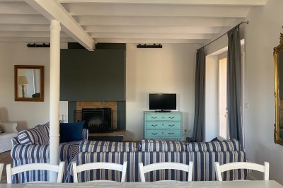 Deux fauteuils en cuir disposés près d'un poêle à bois dans une pièce au mur en bois décorée de cadres et d'une tête d'ours.