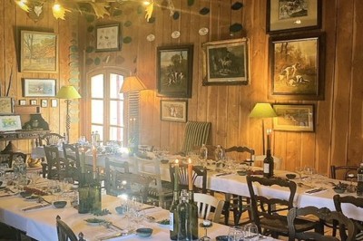 Deux fauteuils en cuir disposés près d'un poêle à bois dans une pièce au mur en bois décorée de cadres et d'une tête d'ours.