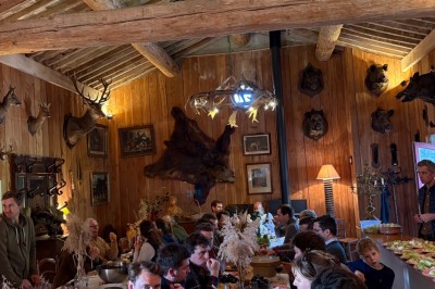 Deux fauteuils en cuir disposés près d'un poêle à bois dans une pièce au mur en bois décorée de cadres et d'une tête d'ours.
