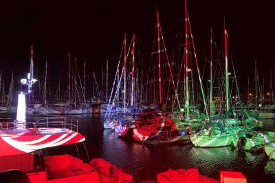 Miniature Vos Nuits Etoilées #7 Voiliers amarrés dans un port de nuit, éclairés par des lumières rouges et vertes.
