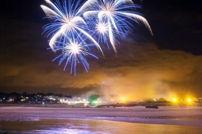 Feux d'artifice avec des traînées dorées et des éclats bleus sur un fond de nuit noire.