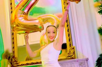 Salle de bain moderne avec lavabo double, miroir, toilettes grises et étagères décorées de plantes et flacons.