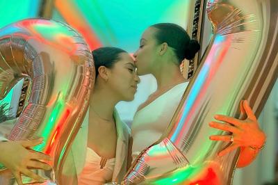 Salle de bain moderne avec lavabo double, miroir, toilettes grises et étagères décorées de plantes et flacons.