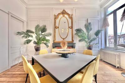 Salle de bain moderne avec lavabo double, miroir, toilettes grises et étagères décorées de plantes et flacons.