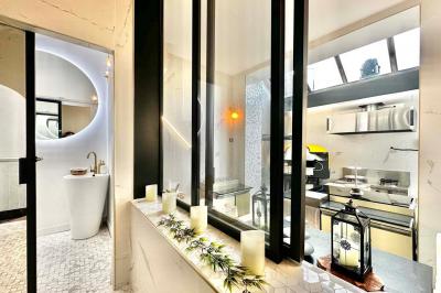 Salle de bain moderne avec lavabo double, miroir, toilettes grises et étagères décorées de plantes et flacons.