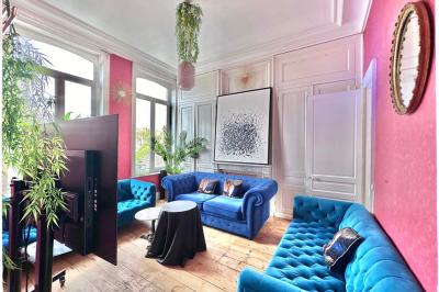 Salle de bain moderne avec lavabo double, miroir, toilettes grises et étagères décorées de plantes et flacons.