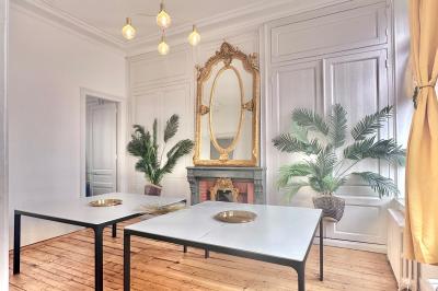 Salle de bain moderne avec lavabo double, miroir, toilettes grises et étagères décorées de plantes et flacons.