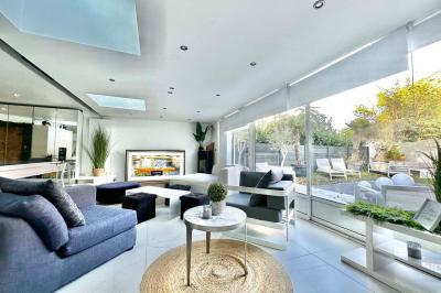 Salle de bain moderne avec lavabo double, miroir, toilettes grises et étagères décorées de plantes et flacons.