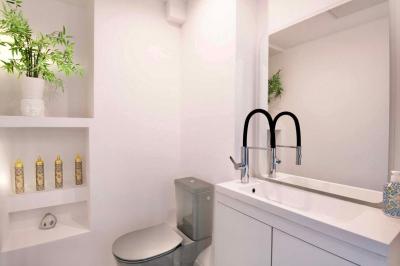 Salle de bain moderne avec lavabo double, miroir, toilettes grises et étagères décorées de plantes et flacons.