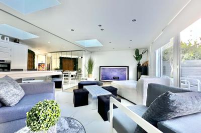 Salle de bain moderne avec lavabo double, miroir, toilettes grises et étagères décorées de plantes et flacons.