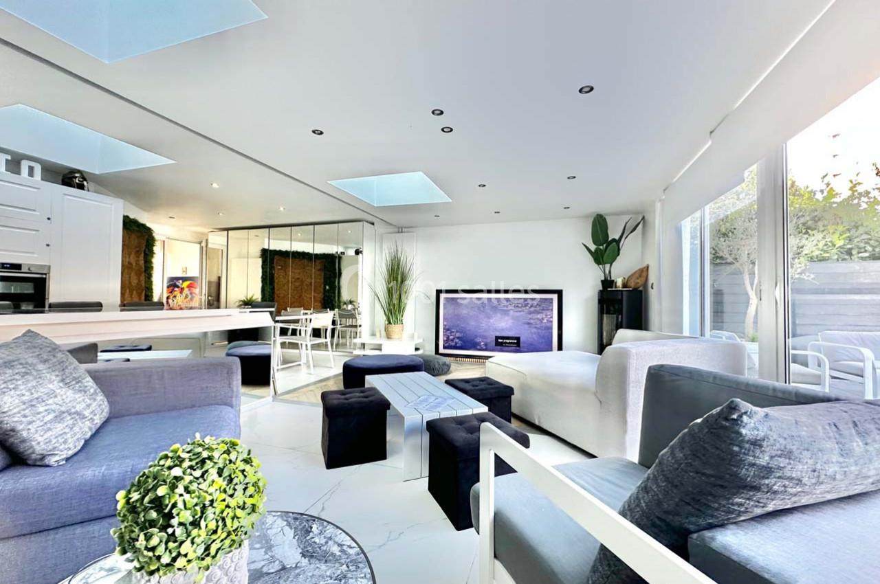 Salon moderne et lumineux avec mobilier contemporain, grandes baies vitrées et décoration végétale.