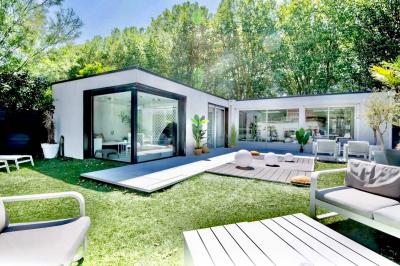 Salle de bain moderne avec lavabo double, miroir, toilettes grises et étagères décorées de plantes et flacons.