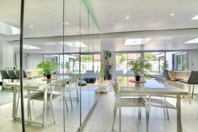 Salle de bain moderne avec lavabo double, miroir, toilettes grises et étagères décorées de plantes et flacons.