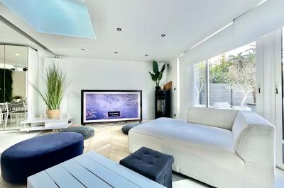 Salle de bain moderne avec lavabo double, miroir, toilettes grises et étagères décorées de plantes et flacons.