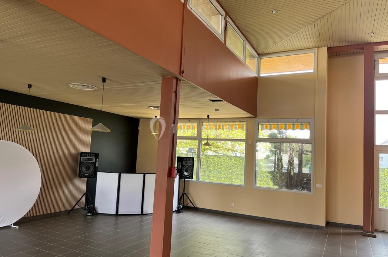 Salle lumineuse avec grandes fenêtres, murs clairs, sol en carrelage gris, équipements audio et fond blanc installés.