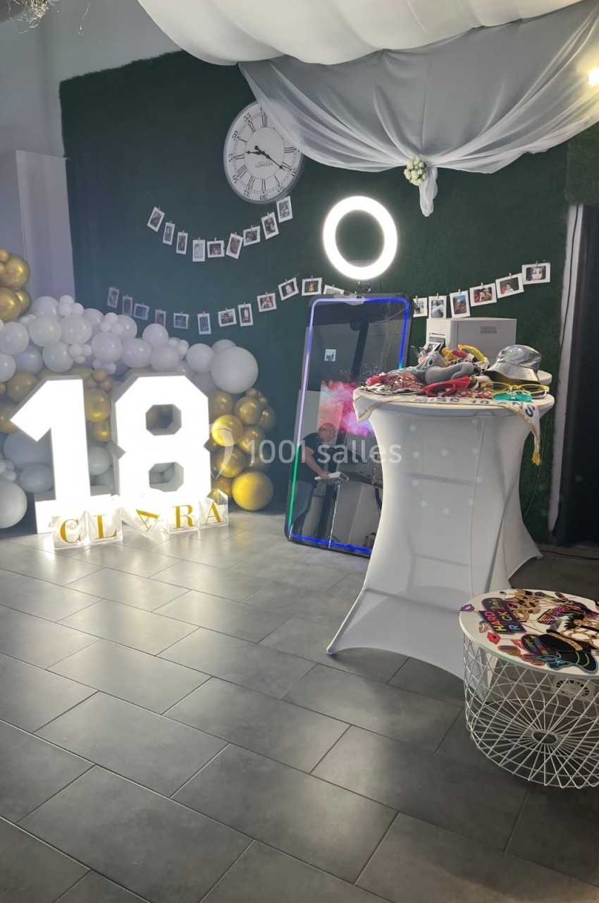 Décoration d'anniversaire avec ballons, chiffres lumineux ’18’, miroir interactif et accessoires sur une table.