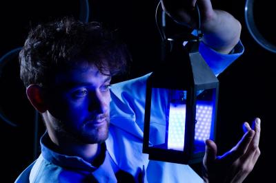 Un jongleur manipule des bâtons rouges dans une galerie lumineuse avec une verrière en arrière-plan.