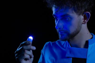 Un jongleur manipule des bâtons rouges dans une galerie lumineuse avec une verrière en arrière-plan.