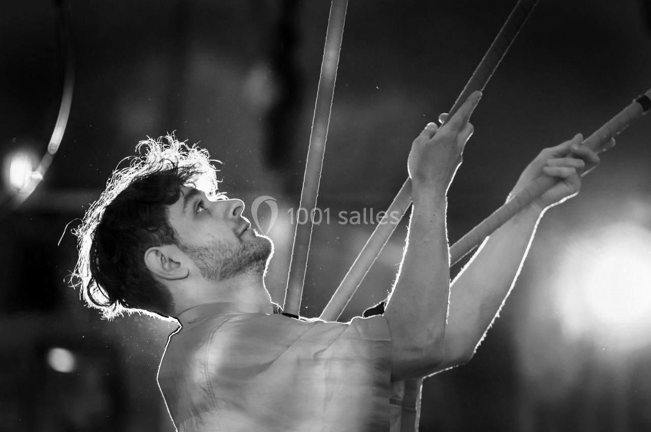 Homme concentré tenant des cordes dans un environnement sombre, éclairé par une lumière vive en arrière-plan.