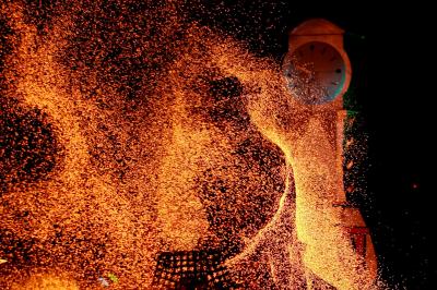 Un jongleur manipule des bâtons rouges dans une galerie lumineuse avec une verrière en arrière-plan.