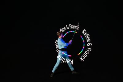 Un jongleur manipule des bâtons rouges dans une galerie lumineuse avec une verrière en arrière-plan.