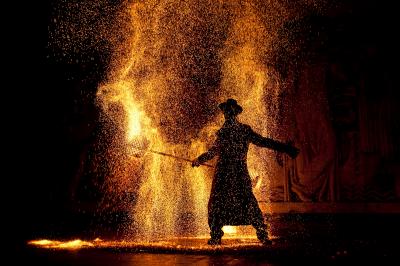 Un jongleur manipule des bâtons rouges dans une galerie lumineuse avec une verrière en arrière-plan.