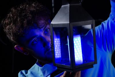 Un jongleur réalise une performance avec des bâtons rouges dans une galerie lumineuse bordée de colonnes.