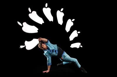 Un jongleur réalise une performance avec des bâtons rouges dans une galerie lumineuse bordée de colonnes.