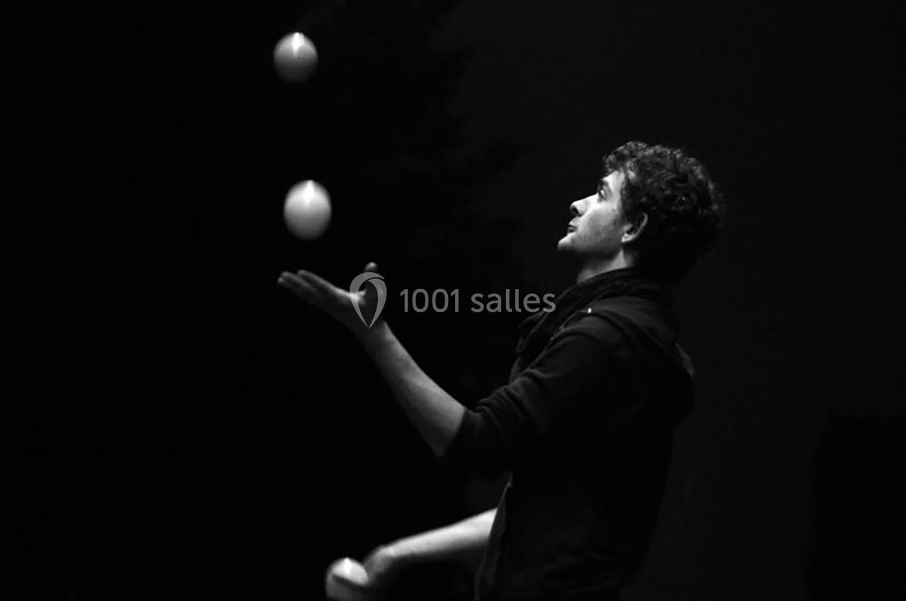 Un homme jongle avec trois balles dans un environnement sombre.