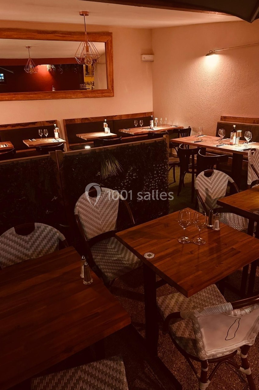 Salle de restaurant avec tables en bois, chaises tressées et éclairage tamisé, ambiance chaleureuse et intimiste.