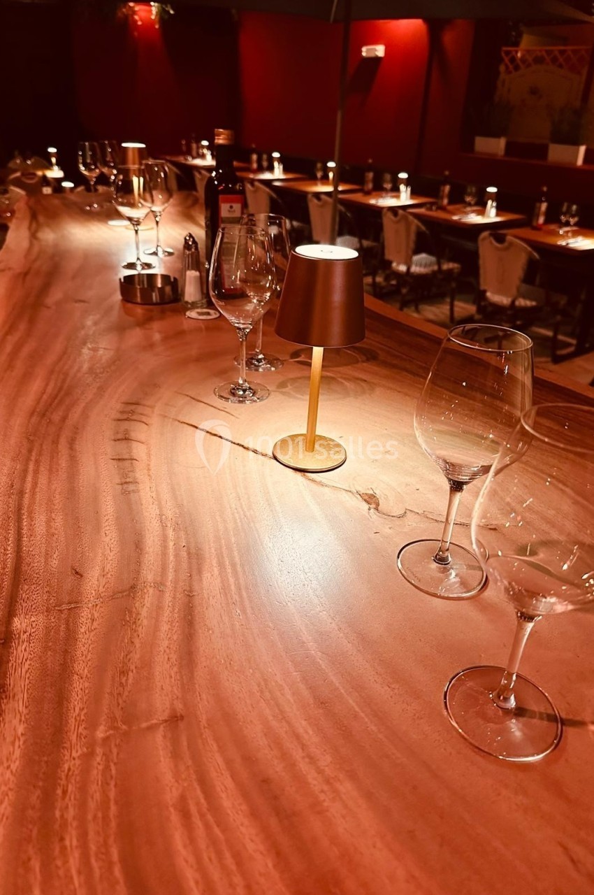 Bar en bois massif avec verres à vin et petites lampes, dans une ambiance chaleureuse et tamisée d'un restaurant.