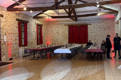 Miniature Soirée privée - Pompier. Salle de réception avec murs en pierre, poutres apparentes, tables dressées et éclairage tamisé.