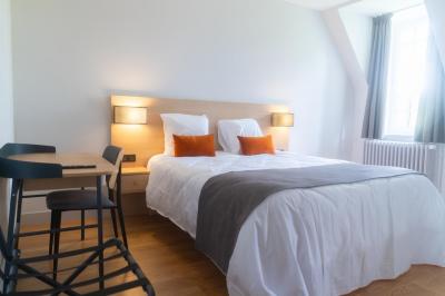 Statue de sphinx en pierre posée sur un socle, entourée de végétation et d'une haie dans un jardin.