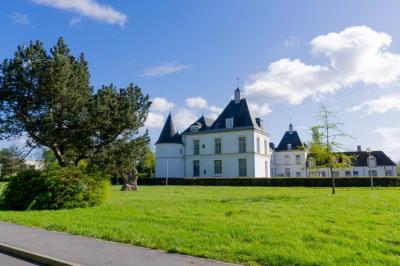 Statue de sphinx en pierre posée sur un socle, entourée de végétation et d'une haie dans un jardin.