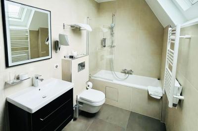 Statue de sphinx en pierre posée sur un socle, entourée de végétation et d'une haie dans un jardin.