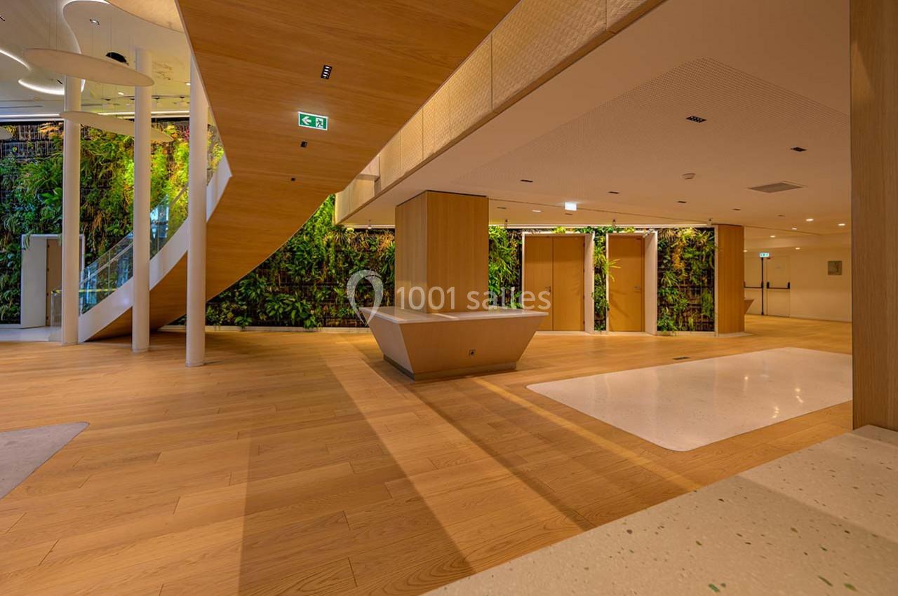 Intérieur moderne avec sol en bois, escalier en colimaçon, mur végétal et éclairage doux.