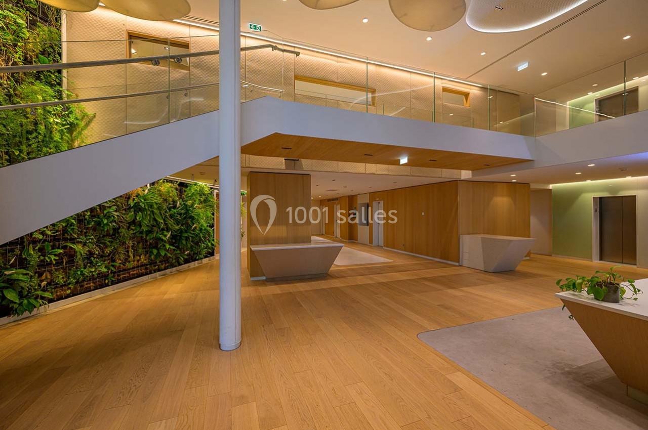 Intérieur moderne avec escalier, murs en bois, sol en parquet et mur végétal dans un espace lumineux.
