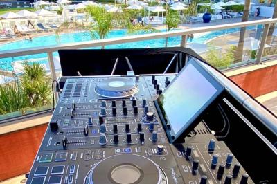 Miniature DJ Mougins (Alpes-Maritimes) - Dj Art Winder #10 Console de DJ avec enceintes sur une terrasse en hauteur, offrant une vue sur la mer et des bâtiments en arrière-plan.