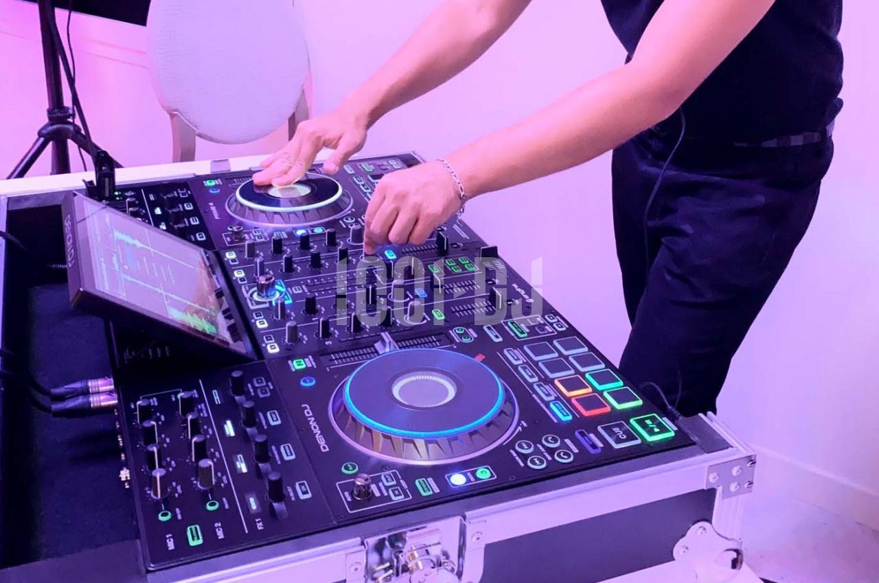 Un DJ mixant de la musique sur une table de mixage lumineuse avec des commandes et des écrans tactiles.