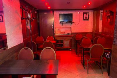 Miniature Location salle Paris 11 (Paris) - Bar de l'Hôtel de la Paix #8 Façade d'un café avec une table extérieure en bois, revêtement en gazon synthétique et intérieur éclairé visible.